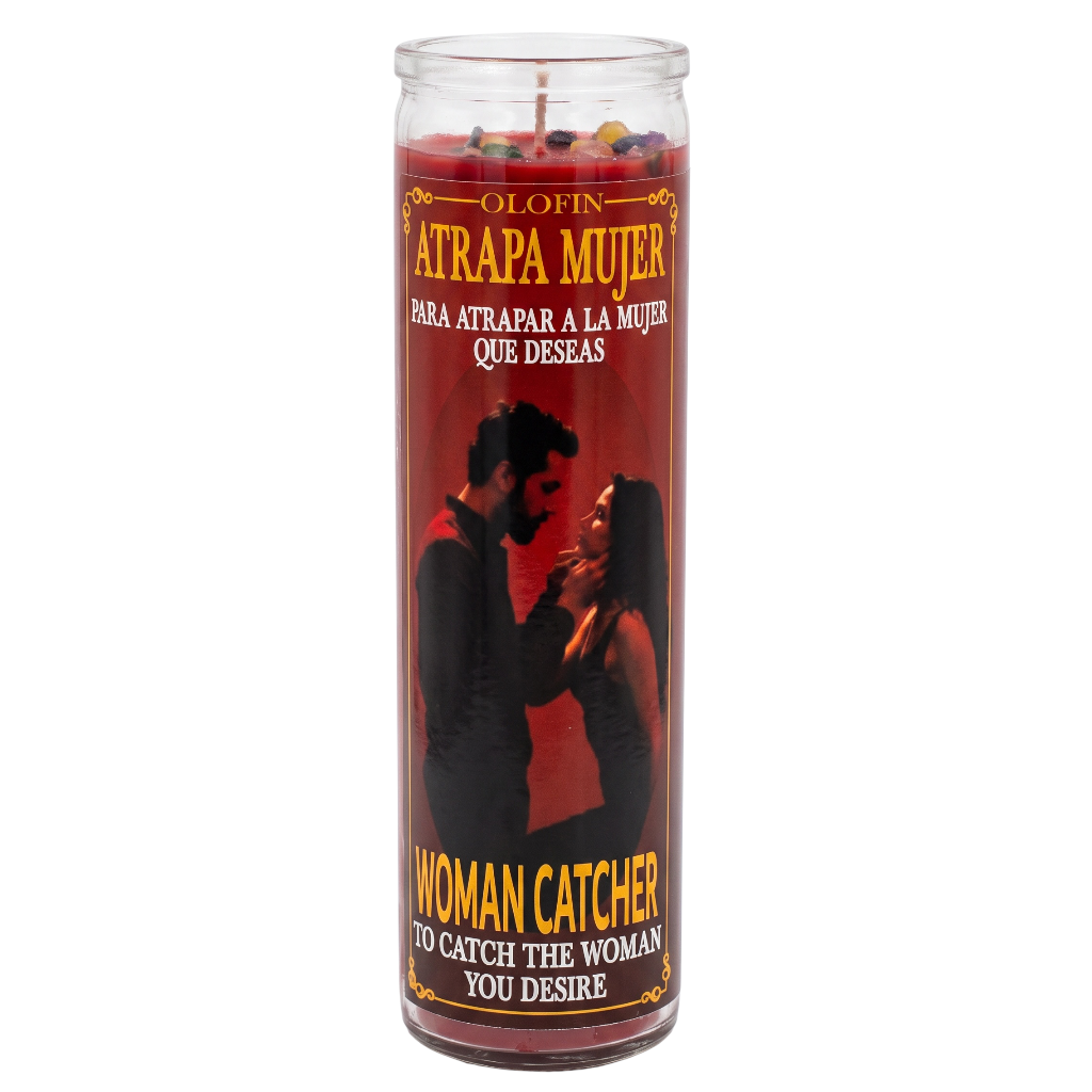 A tall glass jar candle with red wax and a printed label reading 'Atrapa Mujer' and 'Woman Catcher,' featuring a black silhouette of a couple on the front, photographed on a plain white background.