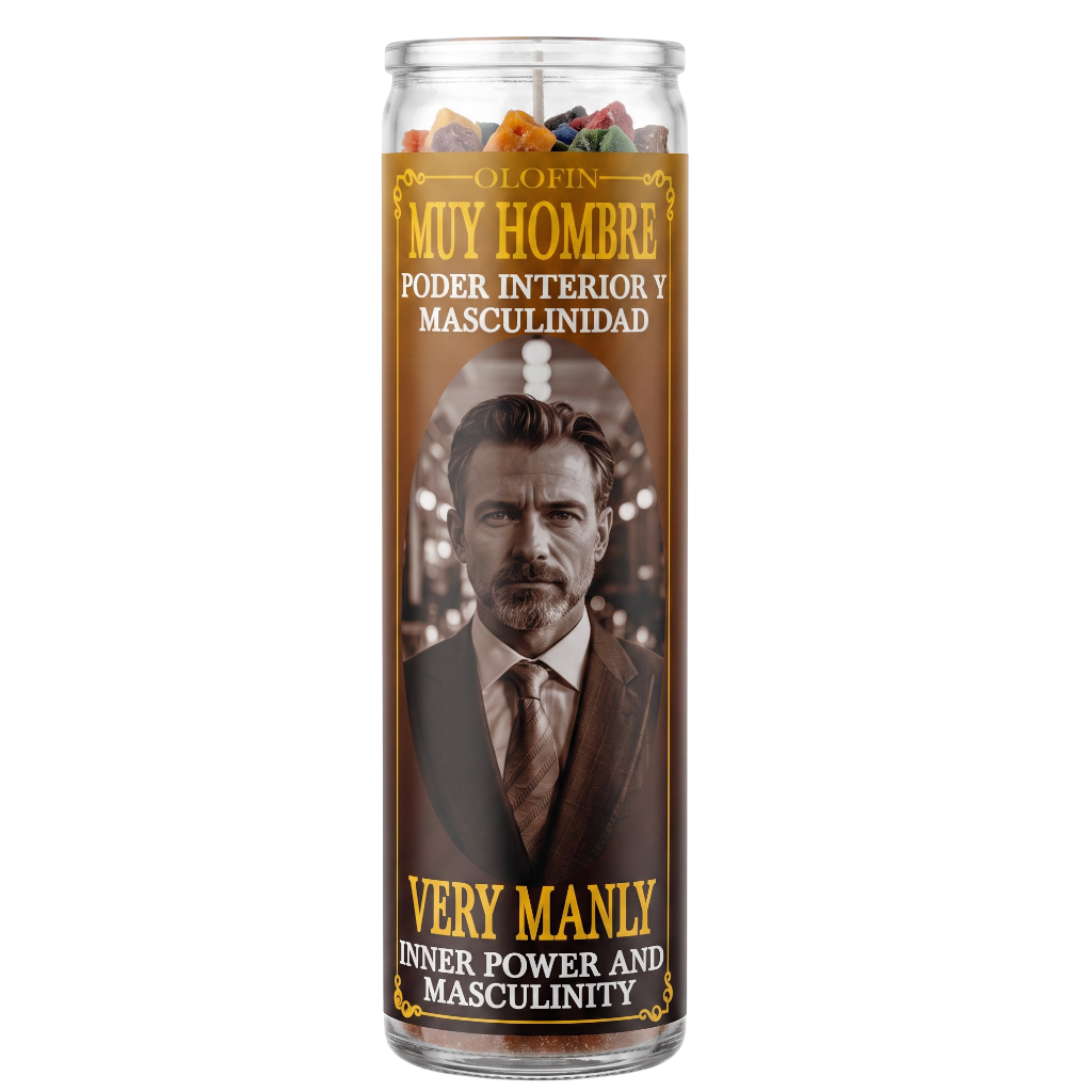 A tall glass jar candle with a brown label featuring a portrait of a man in a suit and Spanish and English text reading 'Muy Hombre' and 'Very Manly'. The candle is shown on a plain white background.