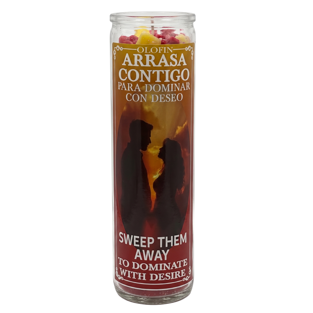 A tall glass jar candle with a Spanish and English label reading 'Olorin Arrasa Contigo Para Dominar Con Deseo' and 'Sweep Them Away To Dominate With Desire,' featuring a red and orange label with black silhouettes of a couple and yellow wax pieces visible at the top.