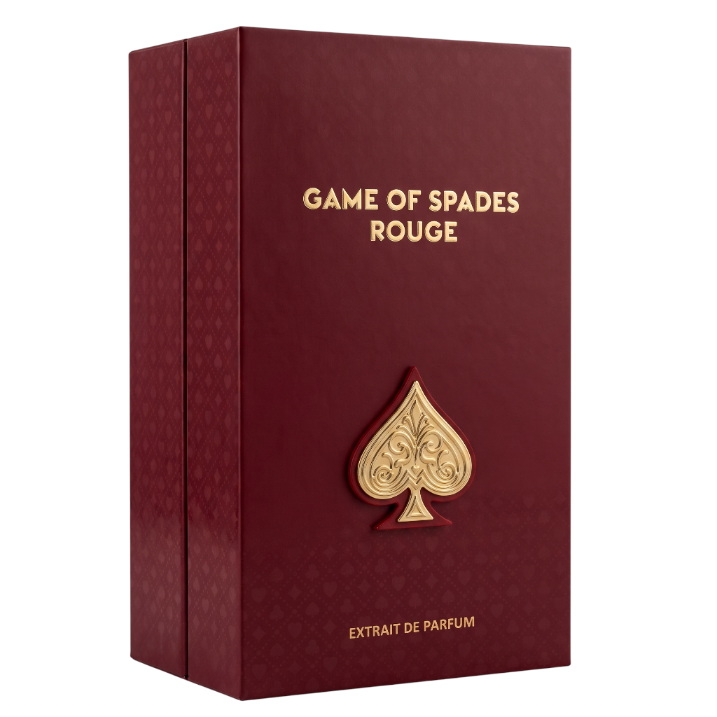 A rectangular dark red perfume box with gold lettering reading 'GAME OF SPADES ROUGE' and 'EXTRAIT DE PARFUM'. A large embossed gold spade symbol is centered on the front.