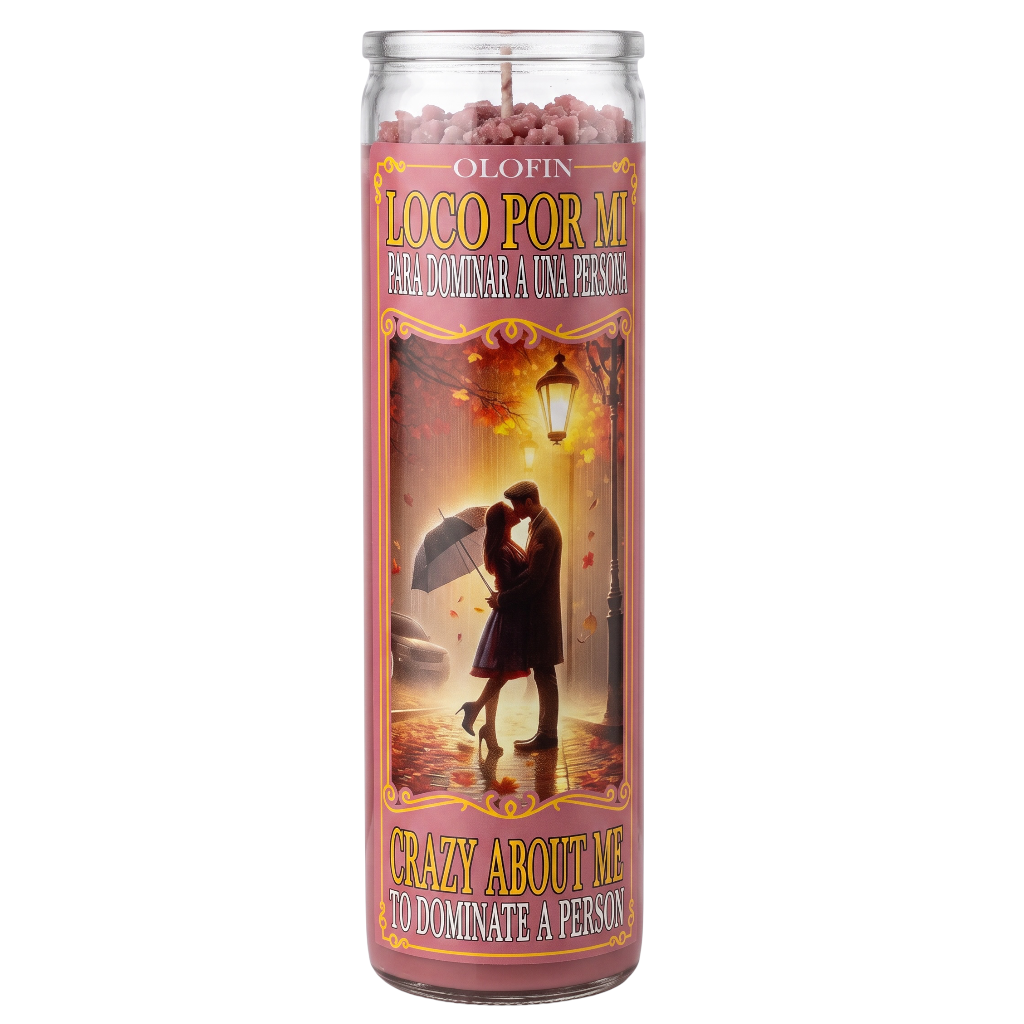 A tall glass jar candle with a pink and gold label reading 'LOCO POR MI' and 'CRAZY ABOUT ME TO DOMINATE A PERSON,' featuring an illustration of a couple under an umbrella in the rain.