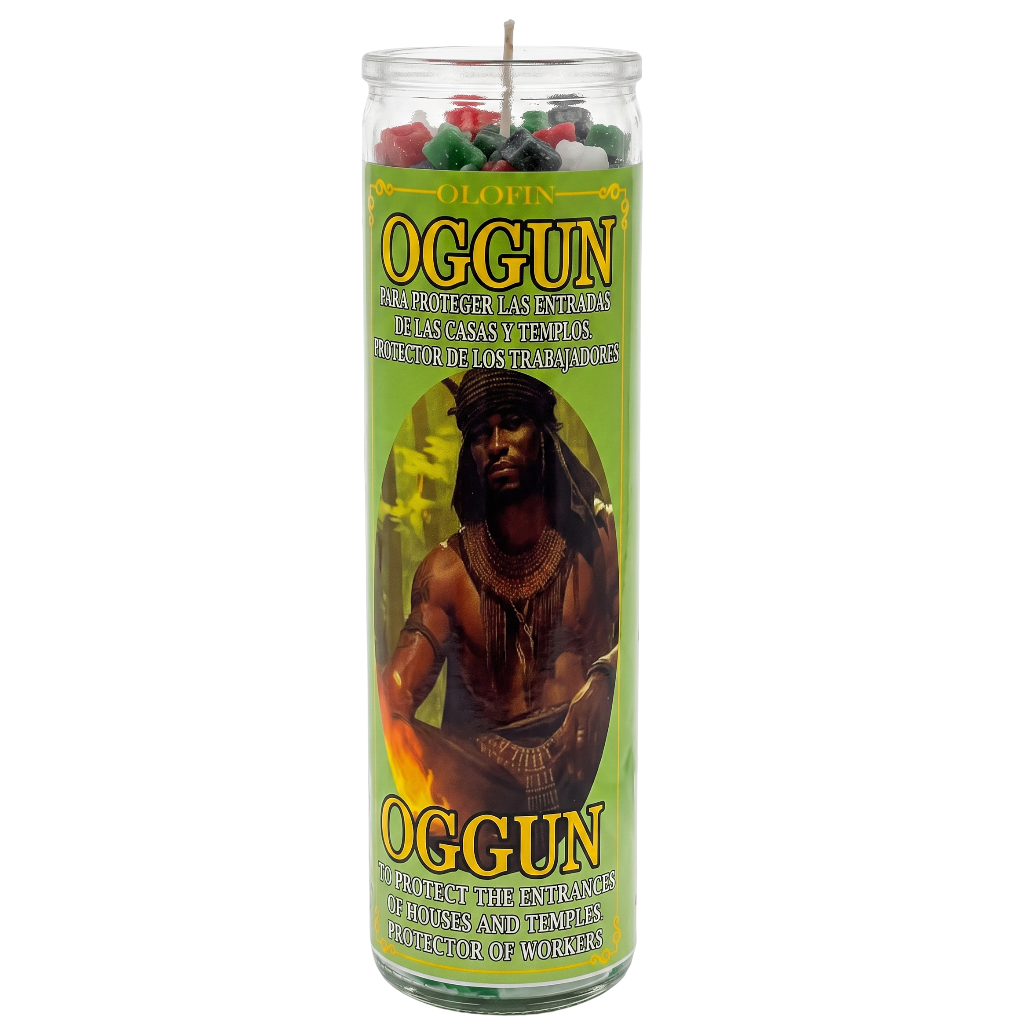 A tall glass jar candle labeled 'Oggun' with a green label featuring an illustration of a man and text in Spanish and English, shown on a plain white background.