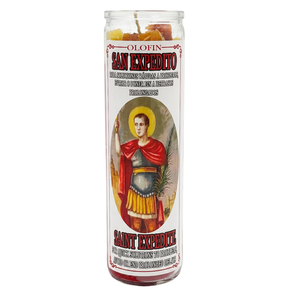 A tall glass jar candle featuring a vintage-style label of Saint Expedicto, with red and black lettering and a depiction of the saint in a red cape and gold armor.
