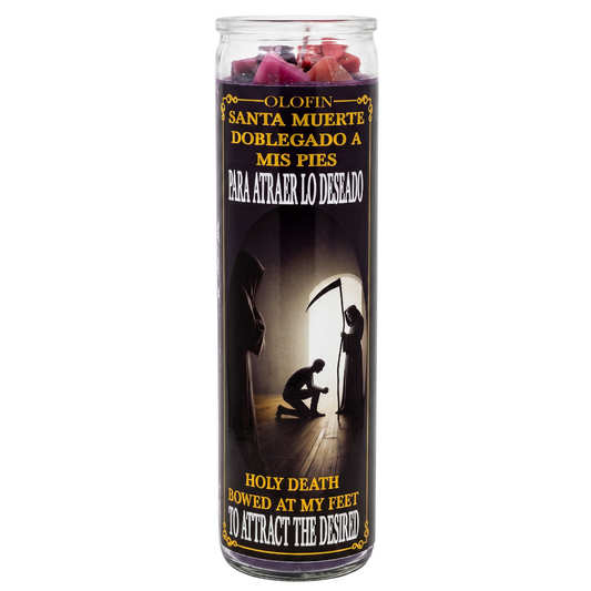 A tall glass jar candle with a black label featuring Spanish and English text, silhouettes of cloaked figures, and pink rose petals visible at the top on a white background.