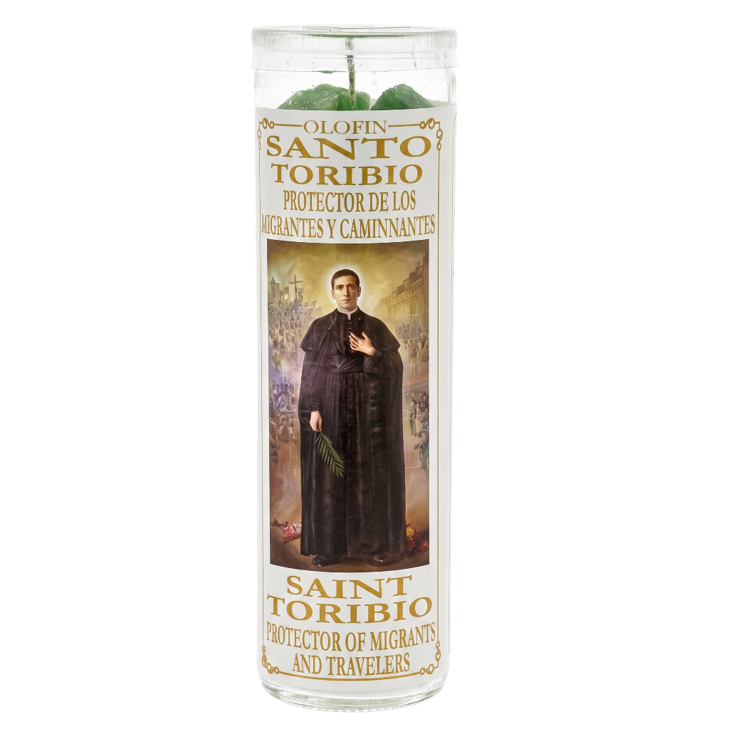 A tall clear glass devotional candle with a printed label featuring Saint Toribio, with green wax visible at the top inside a white background.