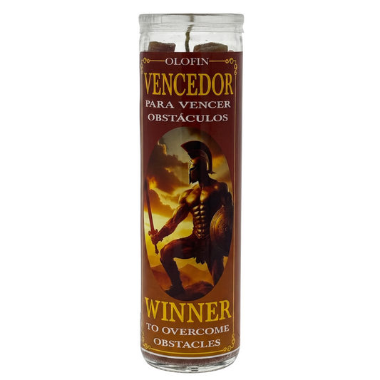 A tall glass jar candle with a brown label featuring a Spartan warrior illustration and Spanish text reading 'Olofin Vencedor para vencer obstáculos' and 'Winner to overcome obstacles.'.