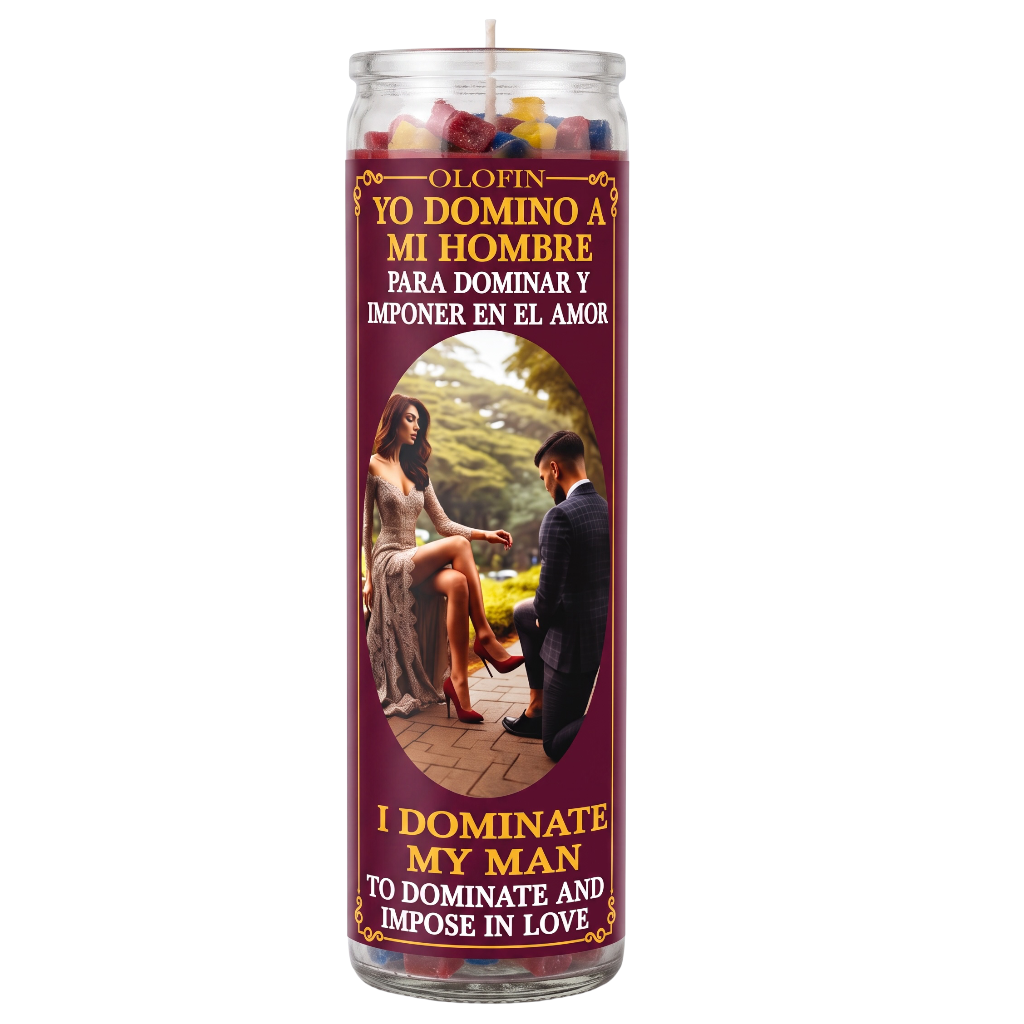 A tall glass jar candle with a maroon label featuring Spanish and English text reading 'Yo Domino a Mi Hombre' and 'I Dominate My Man,' plus a photo of a couple. The candle is shown on a plain white background.