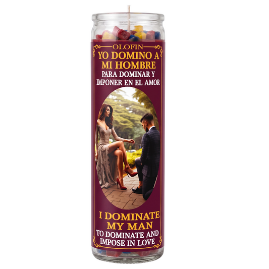 A tall glass jar candle with a maroon label featuring Spanish and English text reading 'Yo Domino a Mi Hombre' and 'I Dominate My Man,' plus a photo of a couple. The candle is shown on a plain white background.